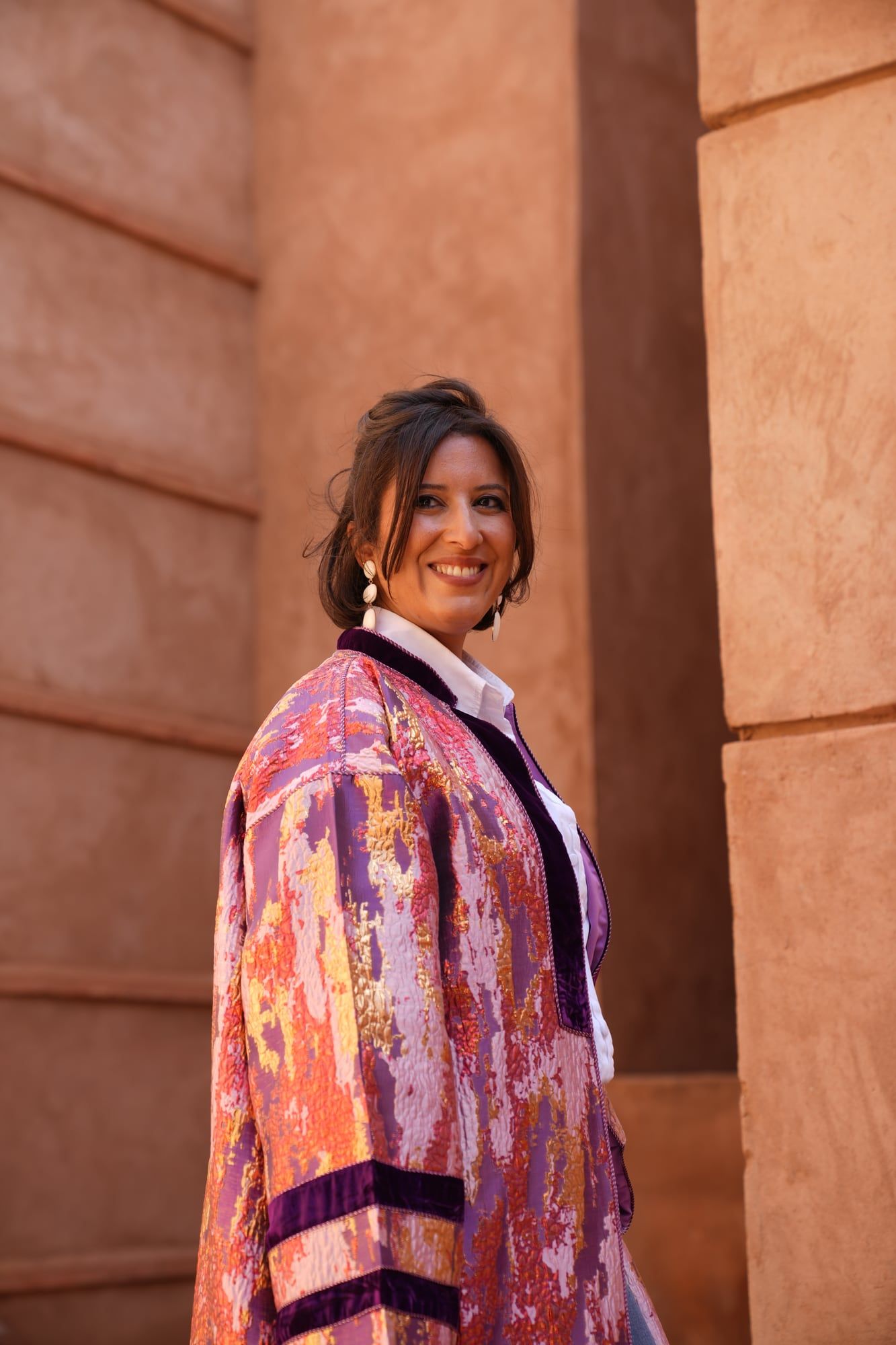 Model in a pink kaftan against terracotta riad walls