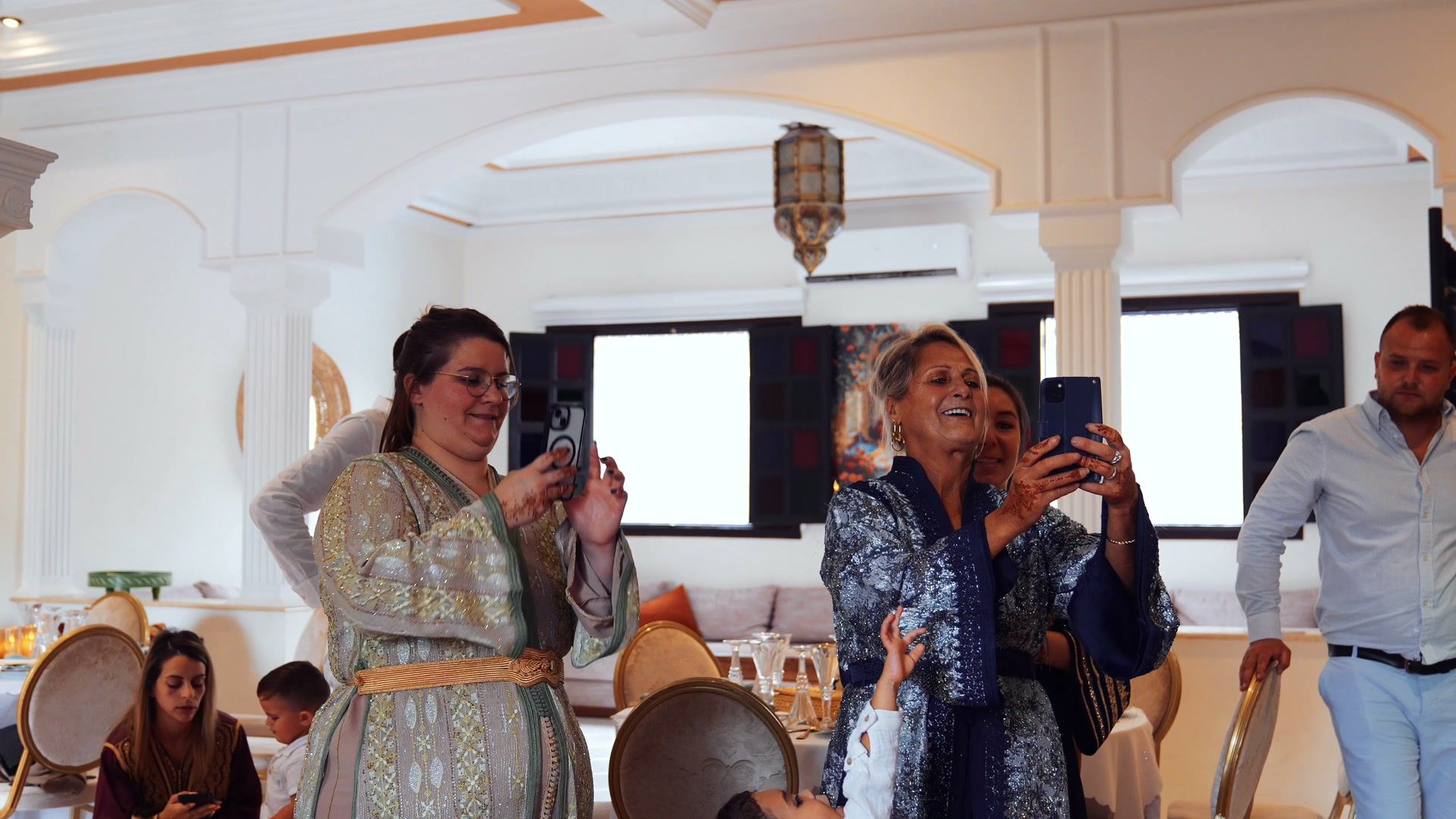 Guests in kaftans filming the couple during the celebration