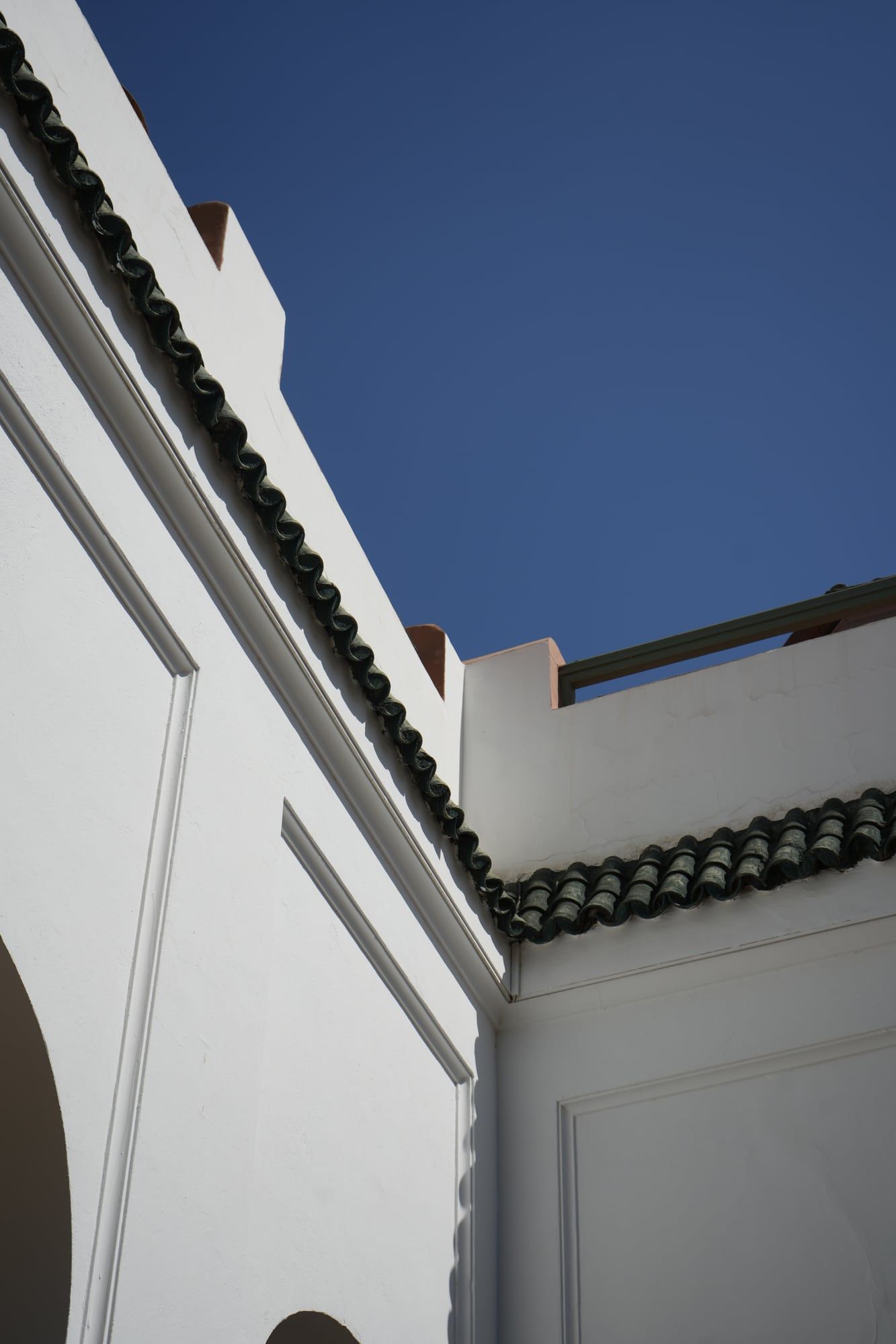 White riad architecture with green tiled roof against a blue sky